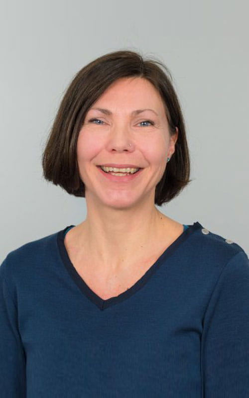 a woman in a blue shirt and smiling at the camera